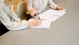 detall de dues persones signant un contracte