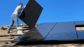 Imatge d'un instal·lador en una teulada posant fotovoltaica